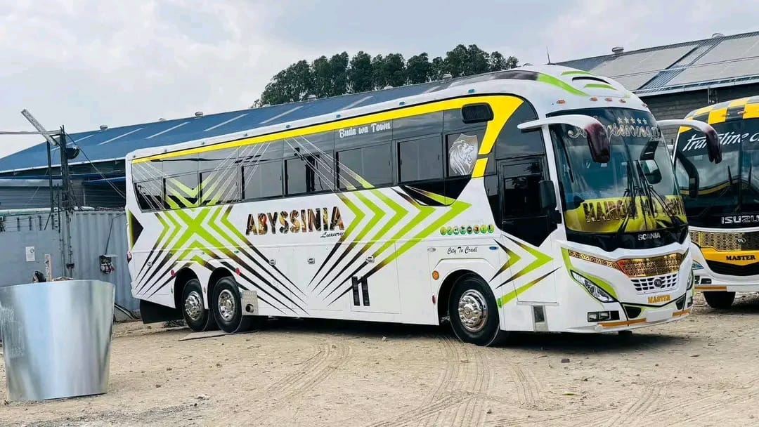 Side profile of an Abyssinia Luxury Coach bus showing the lime-and-gold chevron livery
